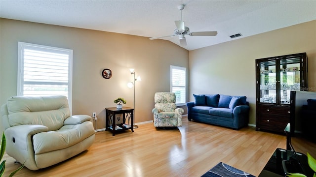 living room featuring light wood finished floors, baseboards, visible vents, a ceiling fan, and lofted ceiling