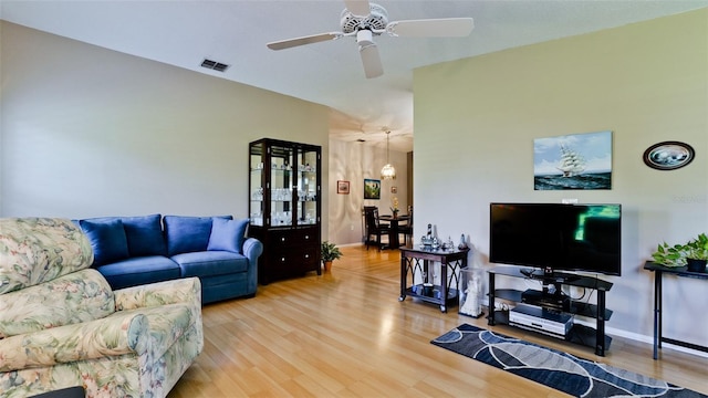 living room featuring ceiling fan with notable chandelier, visible vents, and light wood-style floors