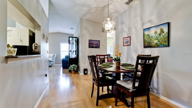 dining space with visible vents, baseboards, an inviting chandelier, light wood-type flooring, and vaulted ceiling