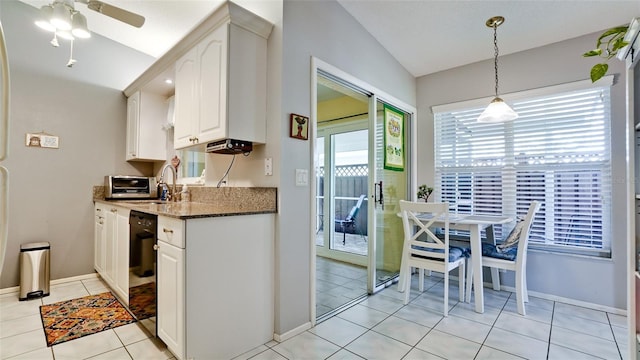 kitchen with baseboards, white cabinets, dark stone counters, and a sink