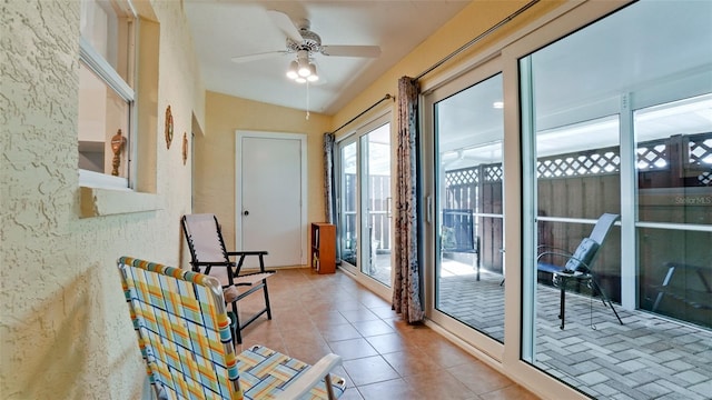 doorway with ceiling fan, lofted ceiling, and light tile patterned floors