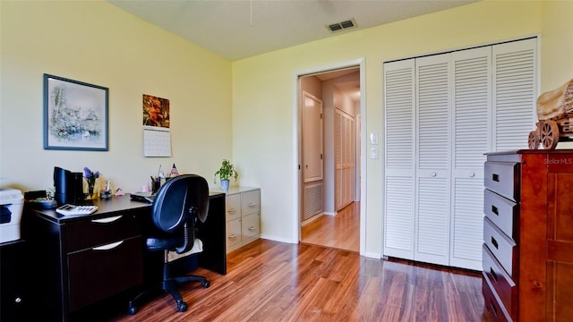 home office with wood finished floors, visible vents, and baseboards