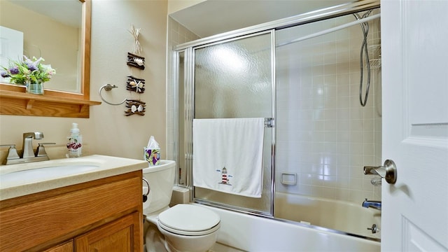 bathroom featuring toilet, enclosed tub / shower combo, and vanity