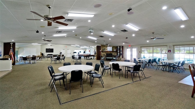 carpeted dining area with a wealth of natural light, visible vents, ceiling fan, and lofted ceiling
