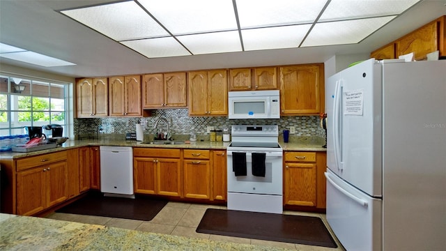 kitchen featuring sink, light tile patterned floors, backsplash, and white appliances