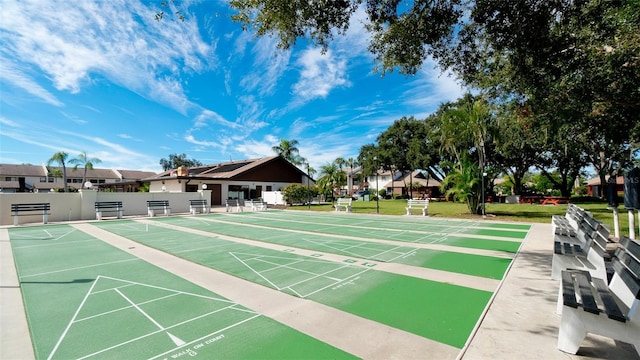 view of home's community with a yard, shuffleboard, and fence