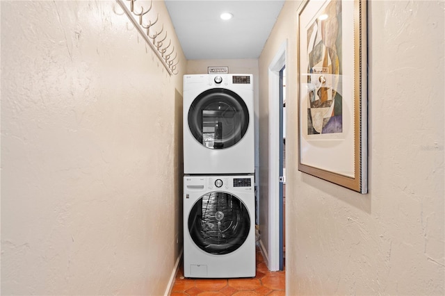 clothes washing area featuring stacked washing maching and dryer and tile patterned floors