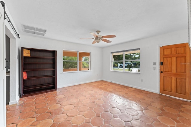 foyer featuring ceiling fan, a barn door, and plenty of natural light