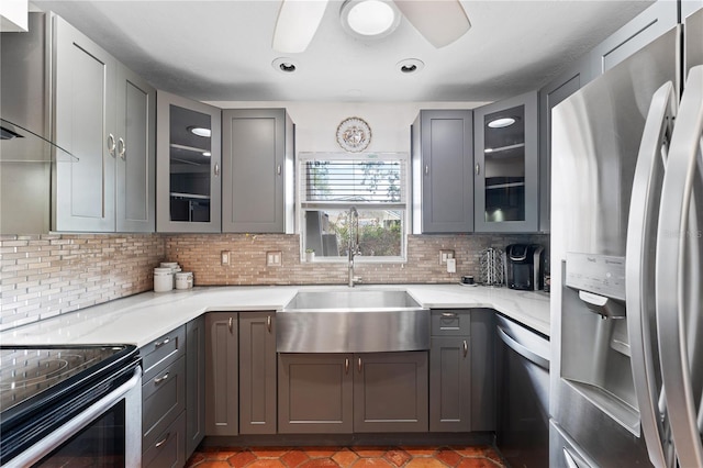 kitchen featuring appliances with stainless steel finishes, gray cabinetry, sink, wall chimney range hood, and tasteful backsplash