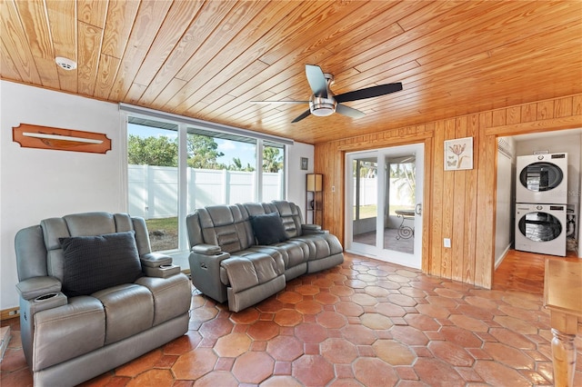 living room featuring stacked washing maching and dryer, wooden ceiling, wooden walls, and plenty of natural light