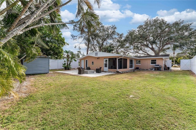 rear view of house with a lawn, a storage unit, a sunroom, and a patio