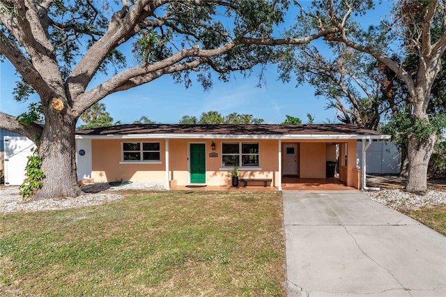 single story home with driveway, stucco siding, an attached carport, and a front yard