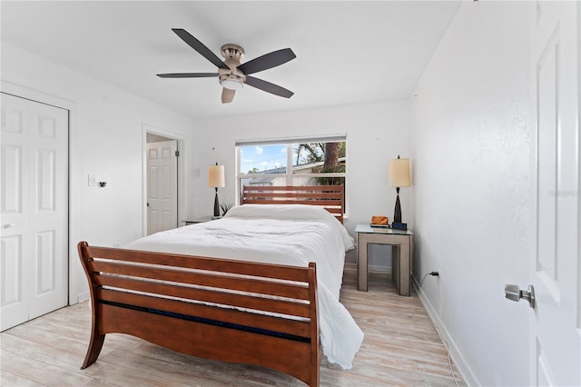 bedroom with a closet, baseboards, a ceiling fan, and light wood-style floors