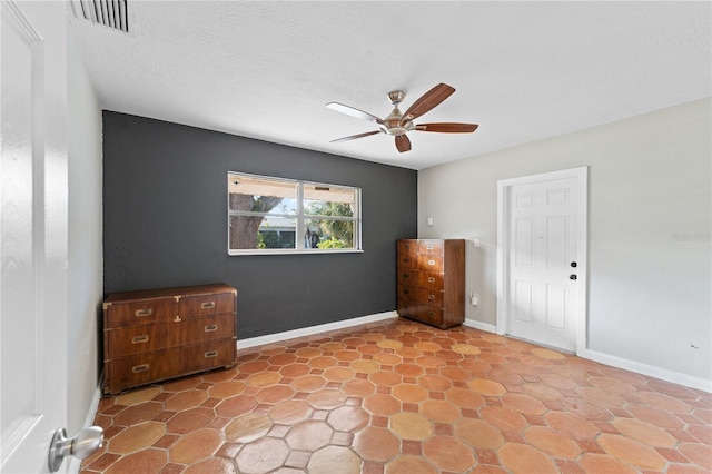 unfurnished bedroom featuring visible vents, baseboards, a textured ceiling, and ceiling fan