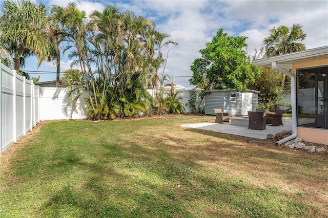 view of yard featuring an outbuilding, a fenced backyard, a shed, and a patio area
