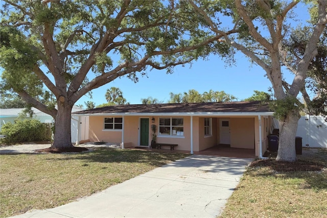 single story home featuring a front yard, driveway, stucco siding, and a carport