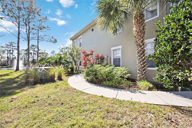 view of side of home with a lawn and stucco siding