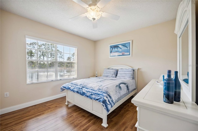 bedroom with dark wood-type flooring, a textured ceiling, baseboards, and a ceiling fan