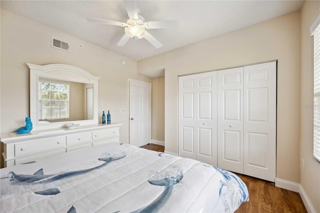 bedroom with a closet, visible vents, ceiling fan, wood finished floors, and baseboards