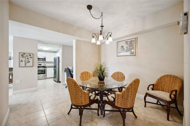 dining area featuring an inviting chandelier, baseboards, a textured ceiling, and light tile patterned flooring