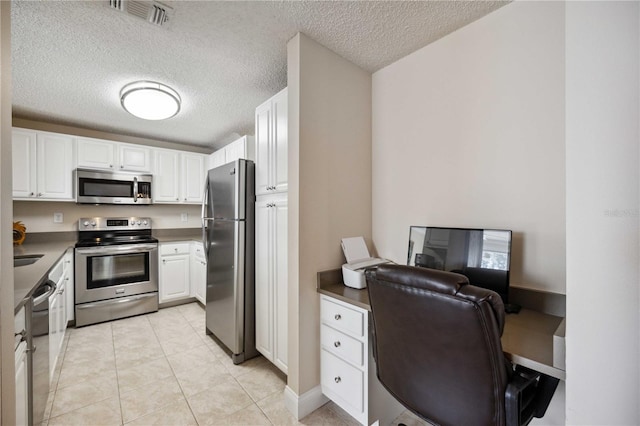 kitchen with stainless steel appliances, light tile patterned floors, visible vents, and white cabinetry