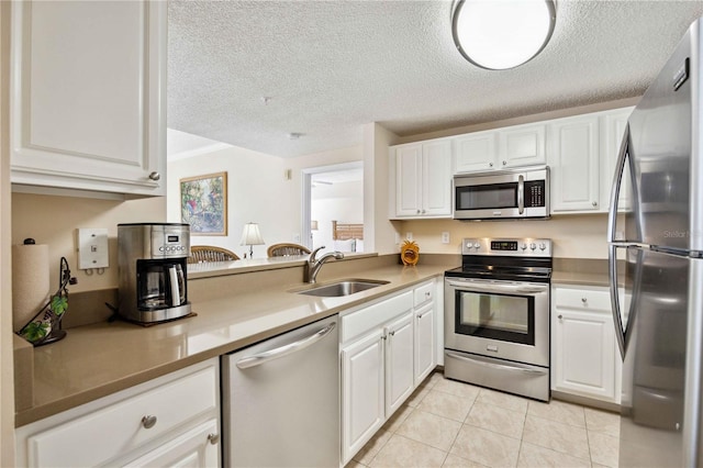 kitchen featuring stainless steel appliances, white cabinetry, a sink, and light tile patterned flooring