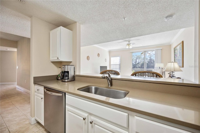 kitchen with a textured ceiling, light tile patterned flooring, a sink, white cabinets, and stainless steel dishwasher