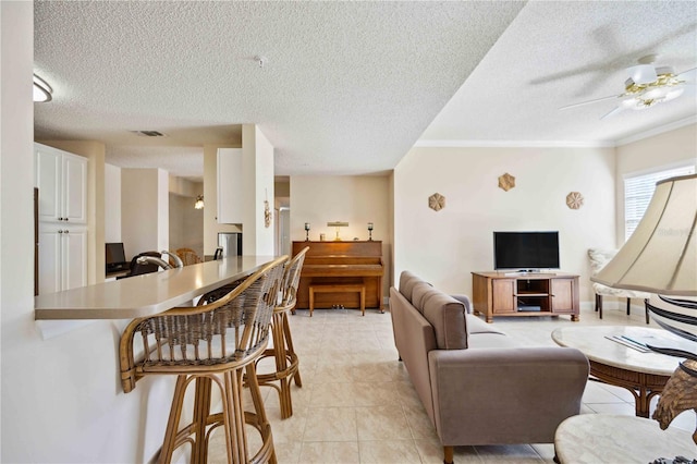 living area with light tile patterned floors, visible vents, a textured ceiling, and a ceiling fan