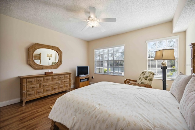 bedroom with dark wood finished floors, a textured ceiling, baseboards, and ceiling fan