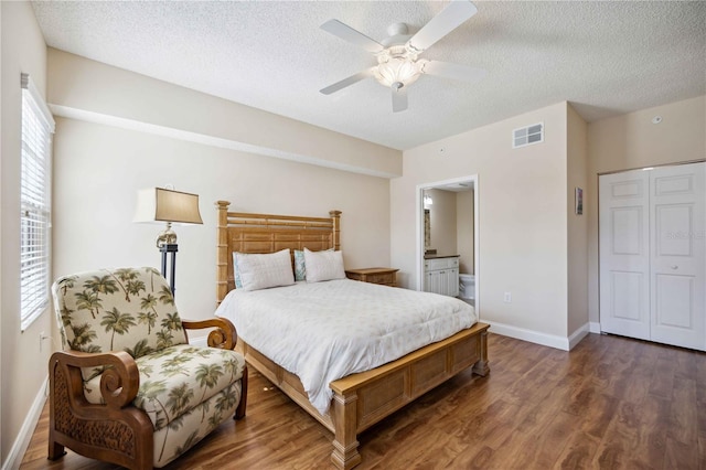 bedroom with visible vents, a textured ceiling, ensuite bath, wood finished floors, and baseboards