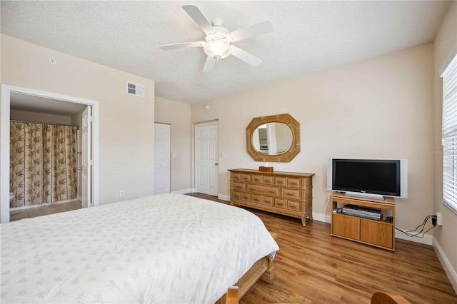 bedroom featuring baseboards, visible vents, ceiling fan, wood finished floors, and a textured ceiling