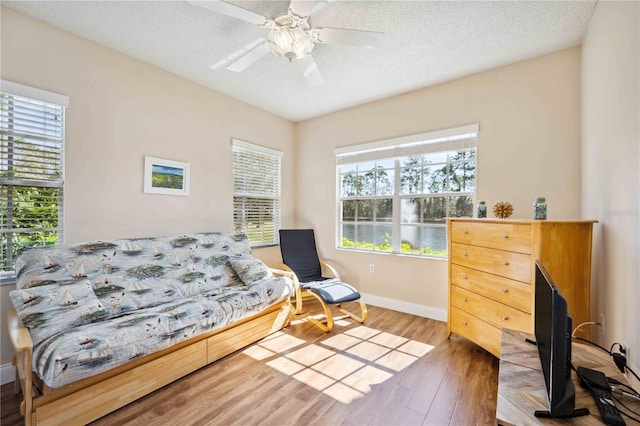 bedroom featuring a textured ceiling, ceiling fan, wood finished floors, and baseboards