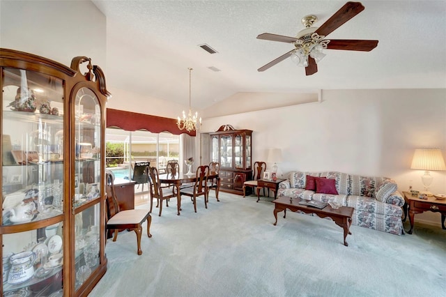 carpeted living room featuring ceiling fan with notable chandelier and vaulted ceiling