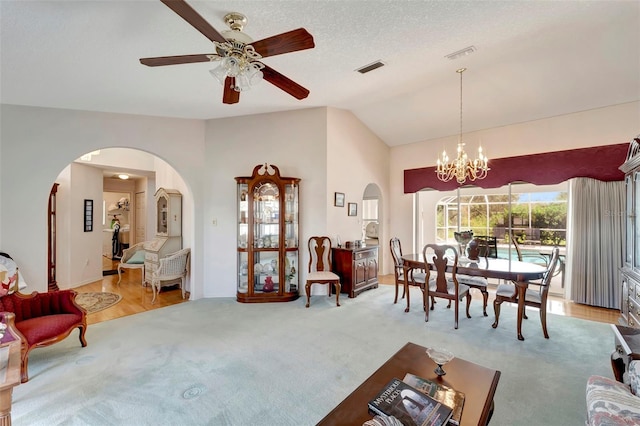 dining space with light hardwood / wood-style flooring, lofted ceiling, a textured ceiling, and ceiling fan with notable chandelier