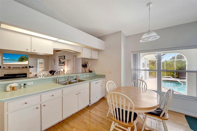 kitchen featuring dishwasher, sink, white cabinetry, pendant lighting, and light hardwood / wood-style flooring