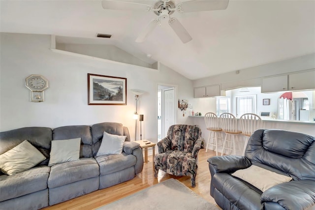 living room with light hardwood / wood-style flooring, ceiling fan, and vaulted ceiling