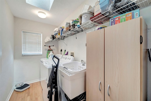 laundry room with a skylight, hardwood / wood-style floors, sink, and separate washer and dryer