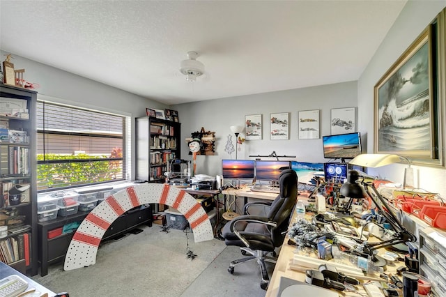 carpeted home office with a textured ceiling and ceiling fan