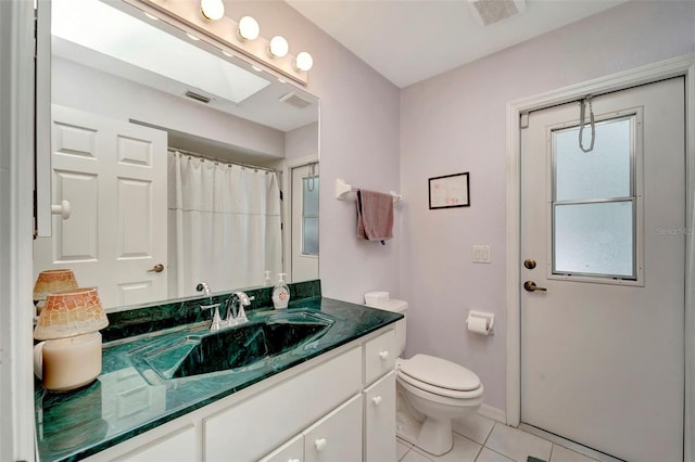 bathroom featuring vanity, toilet, tile patterned floors, and a skylight