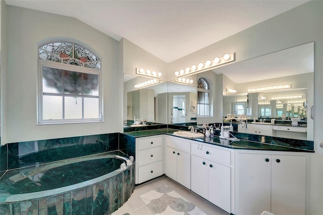 bathroom featuring vanity, vaulted ceiling, a tub, and tile patterned flooring