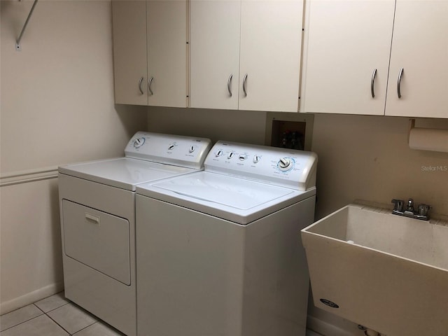 clothes washing area with washer and clothes dryer, light tile patterned flooring, cabinets, and sink