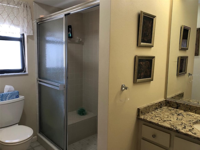 bathroom with tile patterned floors, vanity, toilet, and a shower with shower door