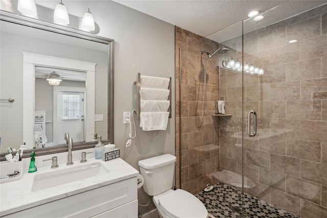 bathroom with vanity, toilet, an enclosed shower, and ceiling fan