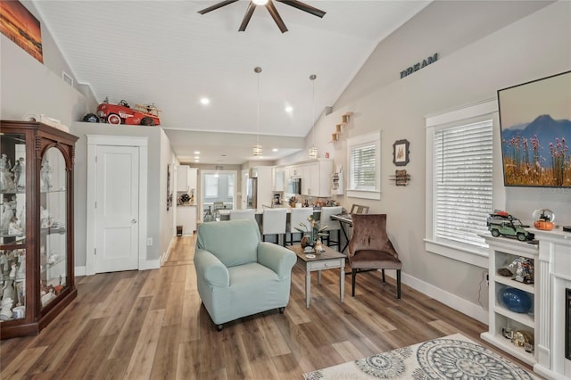 living area featuring ceiling fan, high vaulted ceiling, and light hardwood / wood-style flooring