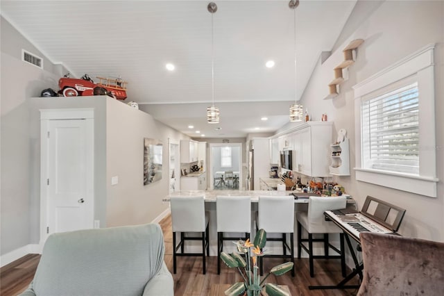 kitchen with kitchen peninsula, white cabinets, hanging light fixtures, and vaulted ceiling