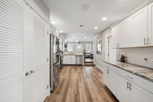 kitchen with white cabinetry, light hardwood / wood-style flooring, light stone counters, and appliances with stainless steel finishes