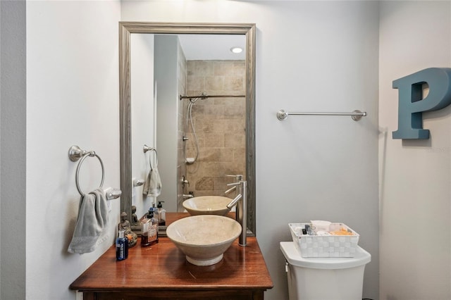 bathroom with tiled shower, vanity, and toilet