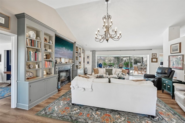 living room with built in features, vaulted ceiling, a high end fireplace, and hardwood / wood-style floors