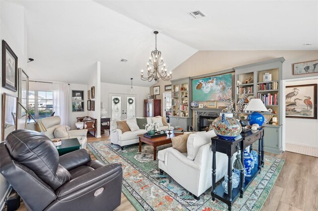 218 Brandywine Cir, Englewood, FL 34223 - living area with a notable chandelier, a fireplace, light wood-style flooring, vaulted ceiling, and visible vents