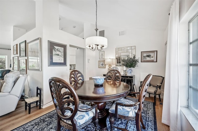 218 Brandywine Cir, Englewood, FL 34223 - dining space with a notable chandelier, visible vents, wood finished floors, and high vaulted ceiling